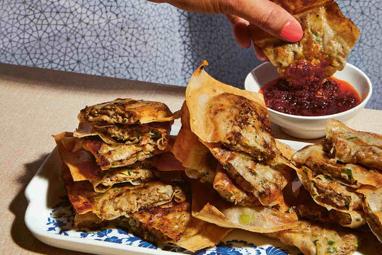 Lamb Martabak (Martabak Daging) - lamb parcels being dipped in a red sauce