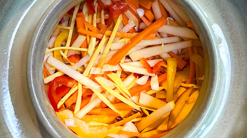 A grey background with bowls of kimchi and fermented food