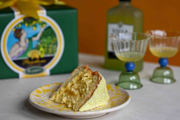 Flamigni Limoncello panettone in a box with a bottle of limoncello, two glasses and a cut slice of panettone